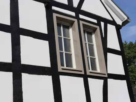 Fassadendetail: schwarz-weißes Fachwerk mit Sprossenfenstern