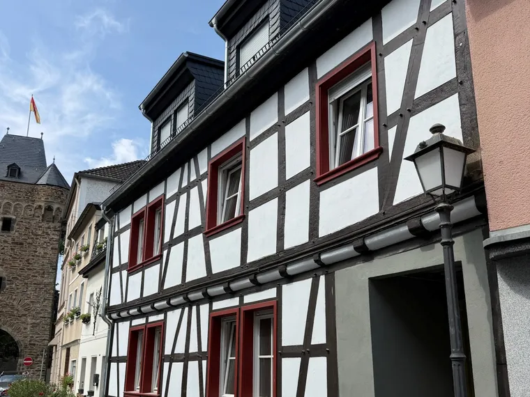 Saniertes Fachwerkhaus mit weißer Fassade und roten Fensterrahmen in historischer Altstadtlage, Front nach Fertigstellung